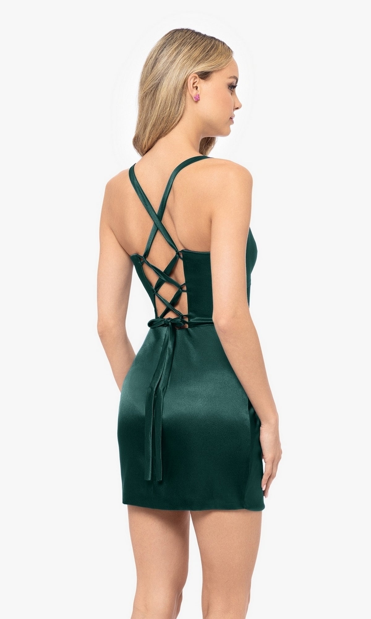 A woman models the Lace-Up Short Sweetheart Homecoming Dress BNC120—a sleeveless, short dark green dress with a crisscross lace-up back—standing against a plain white background.